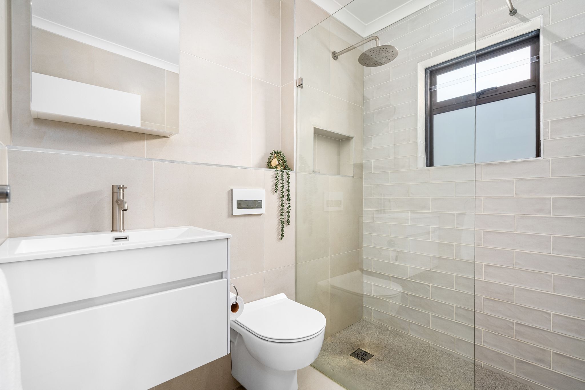 A modern bathroom with a toilet, sink, and shower.