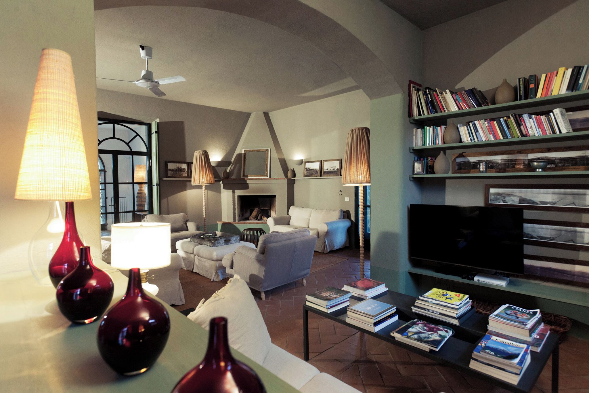 A living room with a fireplace, bookshelves, a television, and decorative lamps.