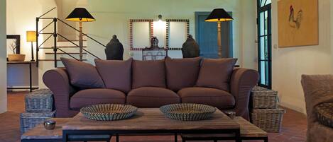 Ein Wohnzimmer mit Sofa, Couchtisch, Lampen und einem Spiegel.