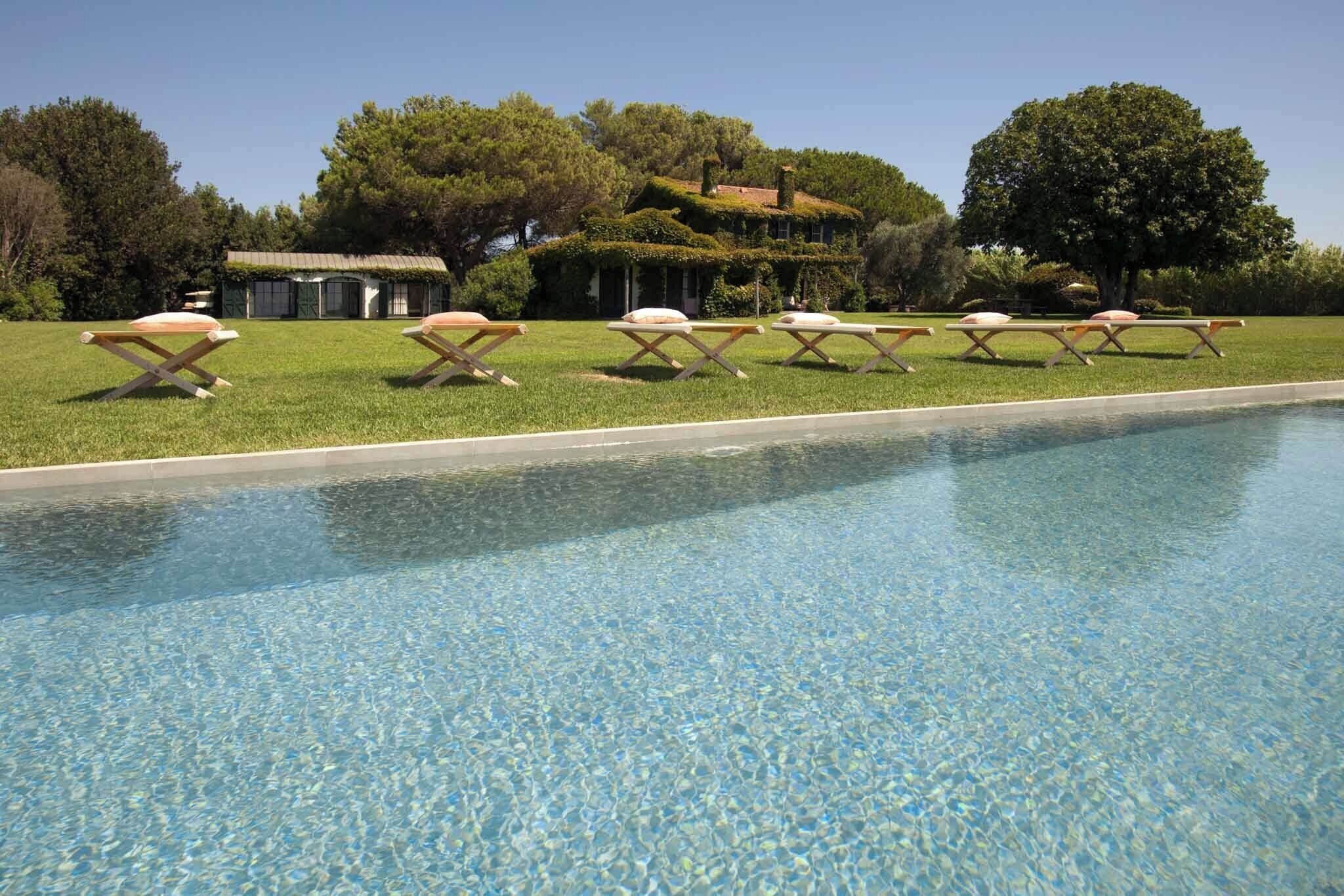 A swimming pool with lounge chairs and a house in the background.