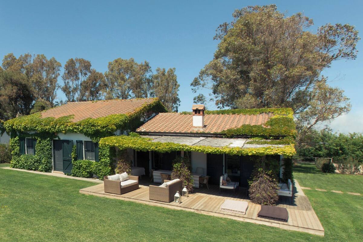 Une maison dotée d’un patio couvert, de mobilier d’extérieur et d’un jardin.