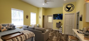 A room with a sofa, a TV, a ceiling fan, and a wall-mounted emblem. - Studio sleeps 4 with Full RV hookup & AC (Kalkaska)