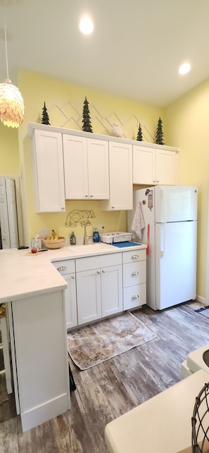 A kitchen with white cabinets, a refrigerator, a wooden countertop, and a hanging light fixture. - Studio sleeps 4 with Full RV hookup & AC (Kalkaska)