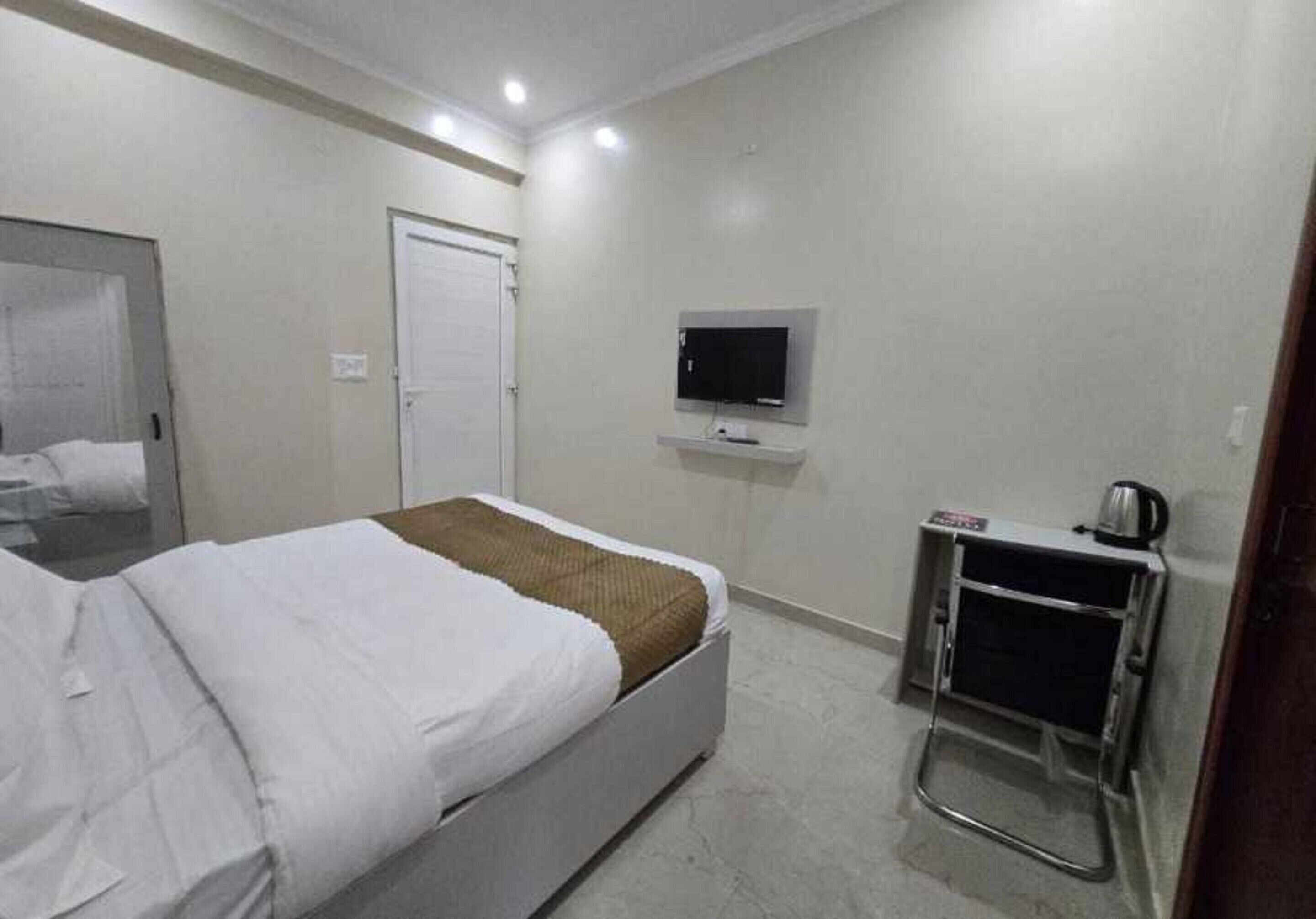 Une chambre d’hôtel équipée d’un lit, d’un téléviseur fixé au mur et d’un petit coin cuisine.