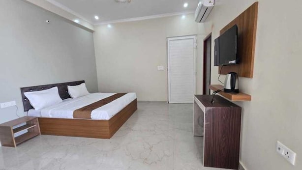 Een slaapkamer met een bed, een bureau, een televisie en een airconditioner.