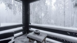A snow-covered wooden bench outside a window with a view of a snowy forest. - Newly Renovated 2BR Cabin in Riihivuori (Muurame)