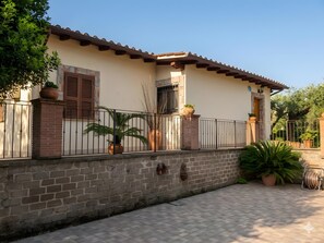 A building with a tiled roof, a brick wall, and a metal fence.