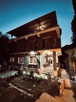 A two-story building with a balcony, a front porch, and a staircase leading to the entrance.