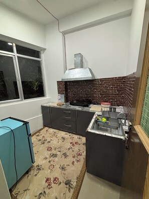 A compact kitchen with a gas stove, a built-in oven, a stainless steel sink, and a window with a view.