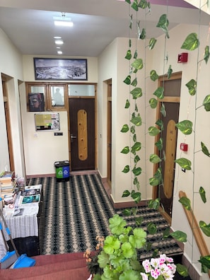 A hallway with patterned flooring, wooden doors, and hanging plants.