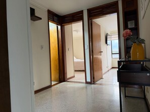 A hallway with a bed in the background, a wooden door, and a vase on a shelf. - Full-service accommodations in the heart of Ibagué (Ibagué)