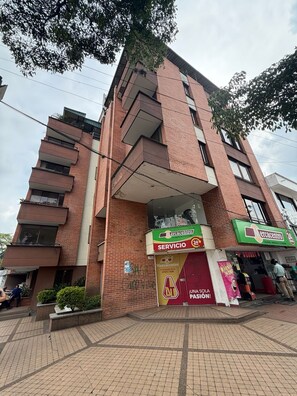 A multi-story building with a brick facade, a ground-level entrance, and a visible ATM sign. - Full-service accommodations in the heart of Ibagué (Ibagué)