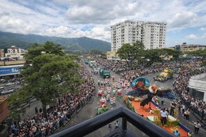 A crowded street parade with spectators, a large dragon float, and buildings in the background. - Full-service accommodations in the heart of Ibagué (Ibagué)