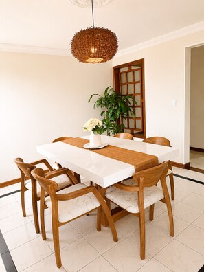 A dining area with a white table, wooden chairs, a woven pendant light, and a potted plant. - Full-service accommodations in the heart of Ibagué (Ibagué)