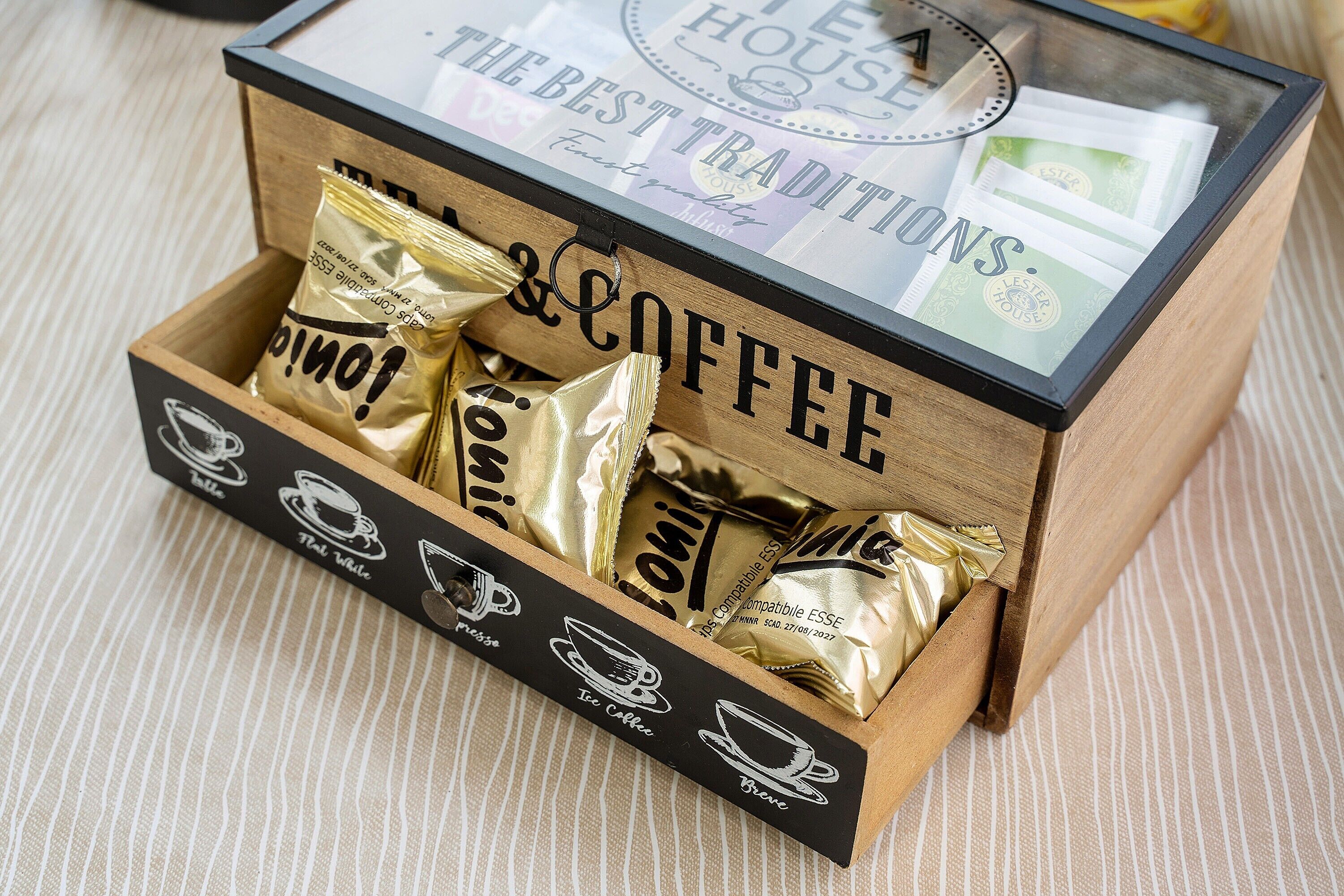 A wooden box with the words 'THE BEST TRADITIONS' and 'COFFEE' on it, containing several gold-colored coffee packets.