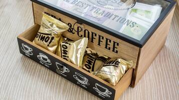 A wooden box with the words 'THE BEST TRADITIONS' and 'COFFEE' on it, containing several gold-colored coffee packets.