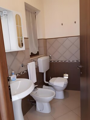 Ein Badezimmer mit Waschbecken, zwei Toiletten, einem Spiegel und einer Duschvorhang.