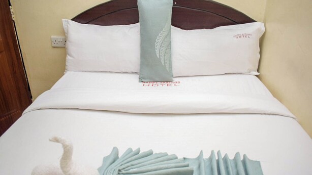 Una cama bien hecha con una colcha blanca, un cojín decorativo y un diseño azul y blanco único en el edredón.