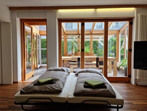 Ein modernes Zimmer mit Bett, Fernseher und großen Fenstern.