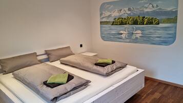 Ein Schlafzimmer mit zwei Betten, einer Wandmalerei von Bergen und Schwänen sowie einem Holzboden.