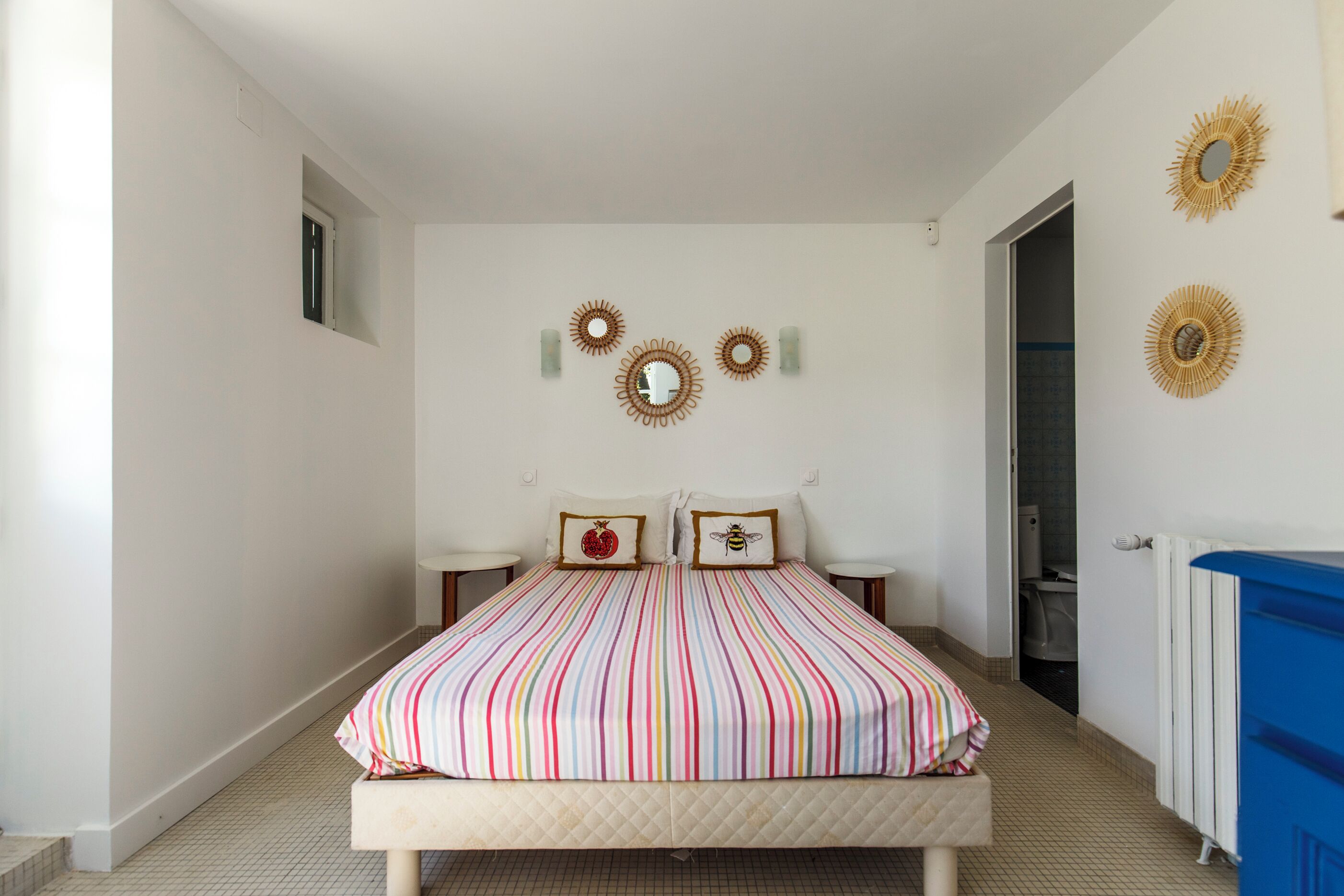 Un dormitorio con una cama, dos mesitas de noche, una ventana y una puerta.