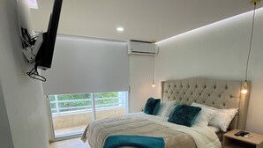 A bedroom with a bed, a nightstand, a wall-mounted TV, an air conditioning unit, and a window with a view. - 1 Bedroom Private Jacuzzi and Direct Beach Access (Cartagena)