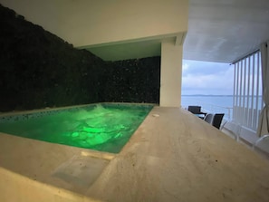 Ein Wellnessbereich mit Pool, einer Steinwand und Blick auf das Meer.