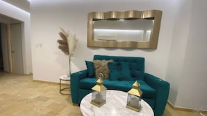 A teal sofa, a round marble table, and a decorative mirror on the wall. - 1 Bedroom Private Jacuzzi and Direct Beach Access (Cartagena)