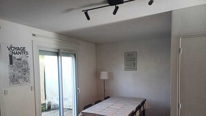 A room with a dining table, chairs, a sofa, a lamp, and a poster on the wall.