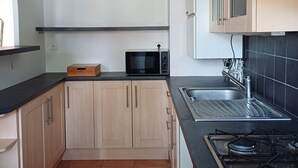 A kitchen with wooden cabinets, a microwave, a gas stove, and a black countertop.