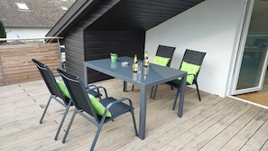 An outdoor patio with a table and chairs, a small potted plant, and a bottle of beer. - Apartment Abel with Balcony, Wi-Fi and Air Conditioning (Oldenburg)