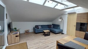 A modern loft-style apartment with a loft bed, a sectional sofa, a dining area, and a kitchenette. - Apartment Abel with Balcony, Wi-Fi, Charging Station & AC near Hospital and Rehab Center (Oldenburg)