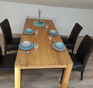 A dining table set with plates, glasses, and cutlery, surrounded by chairs. - Apartment Abel with Balcony, Wi-Fi and Air Conditioning (Oldenburg)