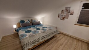 A bedroom with a bed, bedside lamps, a radiator, and wall art. - Apartment Abel with Balcony, Wi-Fi, Charging Station & AC near Hospital and Rehab Center (Oldenburg)