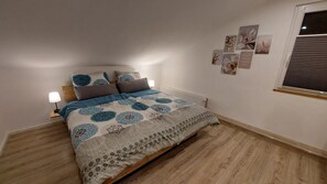 Un dormitorio con cama, lámparas de noche, radiador y cuadros en la pared.
