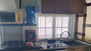 A kitchen with a microwave, coffee maker, sink, and wooden cabinets.