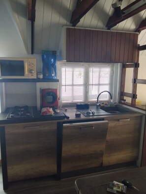 A kitchen with a microwave, coffee maker, sink, and wooden cabinets. - Beachfront cottage (Neuvic)
