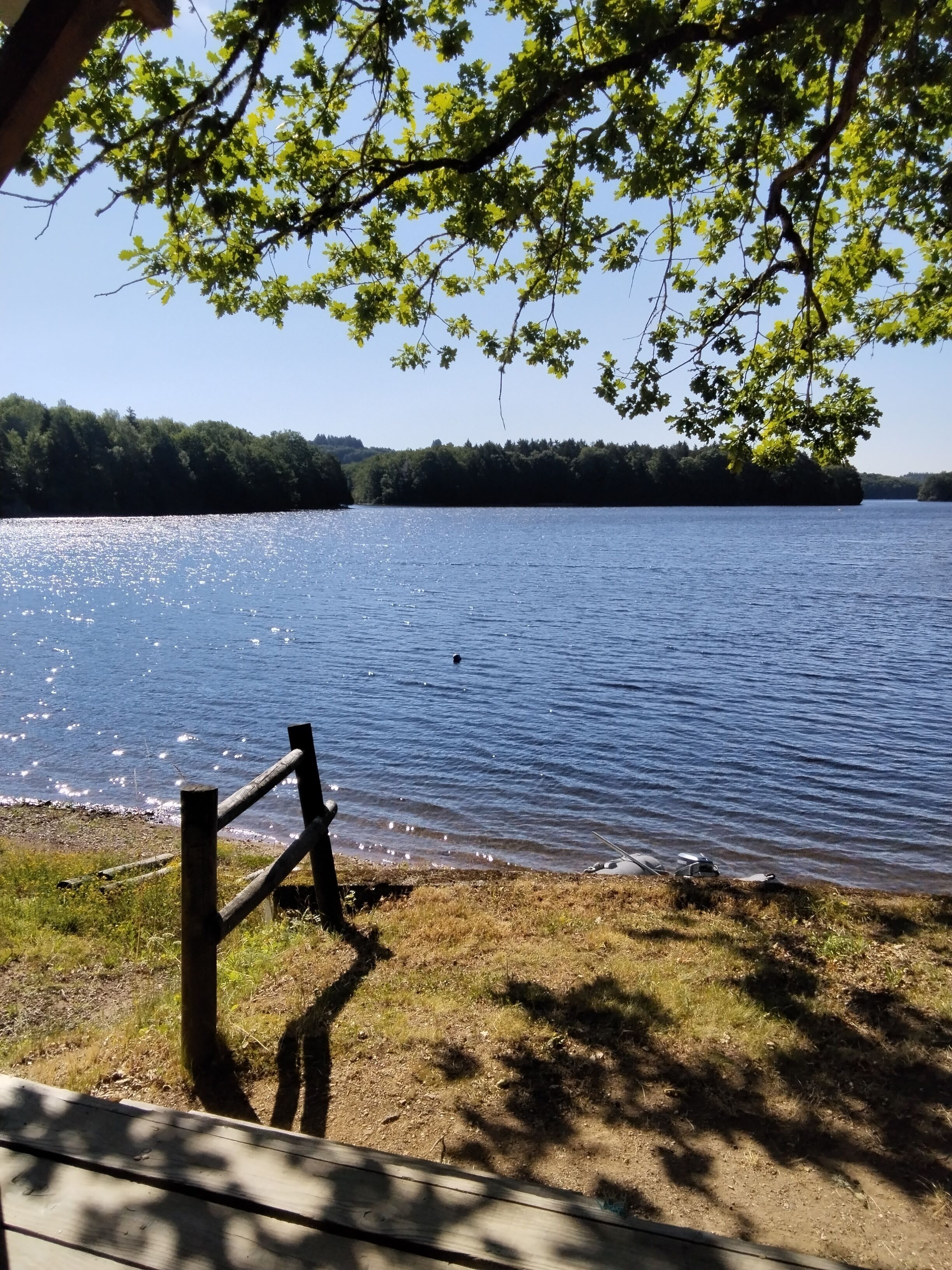 Vista sul lago con una veranda in legno, una recinzione e cielo sereno.