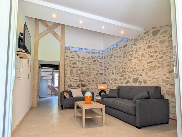 Una sala de estar con una pared de piedra, un sofá, una mesa de centro y una lámpara.