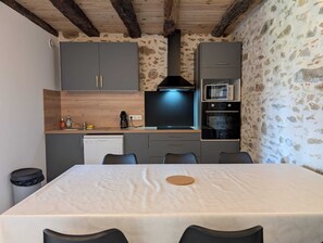 A compact kitchen with grey cabinets, a black range hood, a microwave, and a dishwasher. - Gîte du Bosquet (Oradour-sur-Glane)