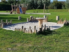 Ein Spielplatz mit einer Rutsche aus Holz und Klettergerüsten.