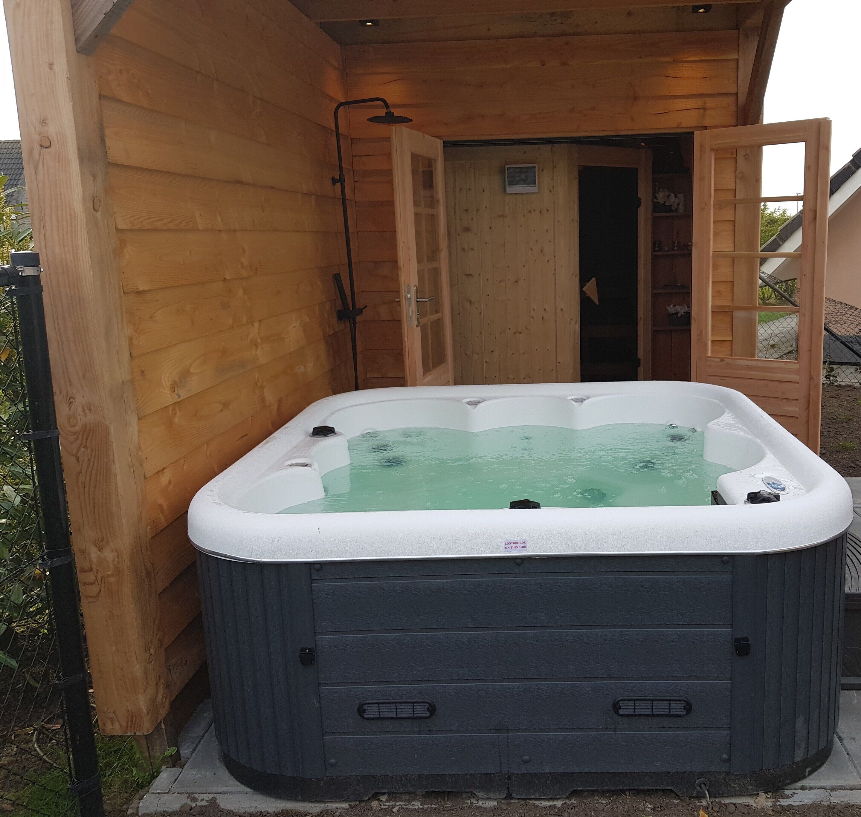 A hot tub in a wooden cabin with a door leading to a room.