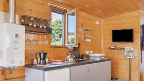 A wooden interior with a kitchen area, including a stove, sink, and a television mounted on the wall.