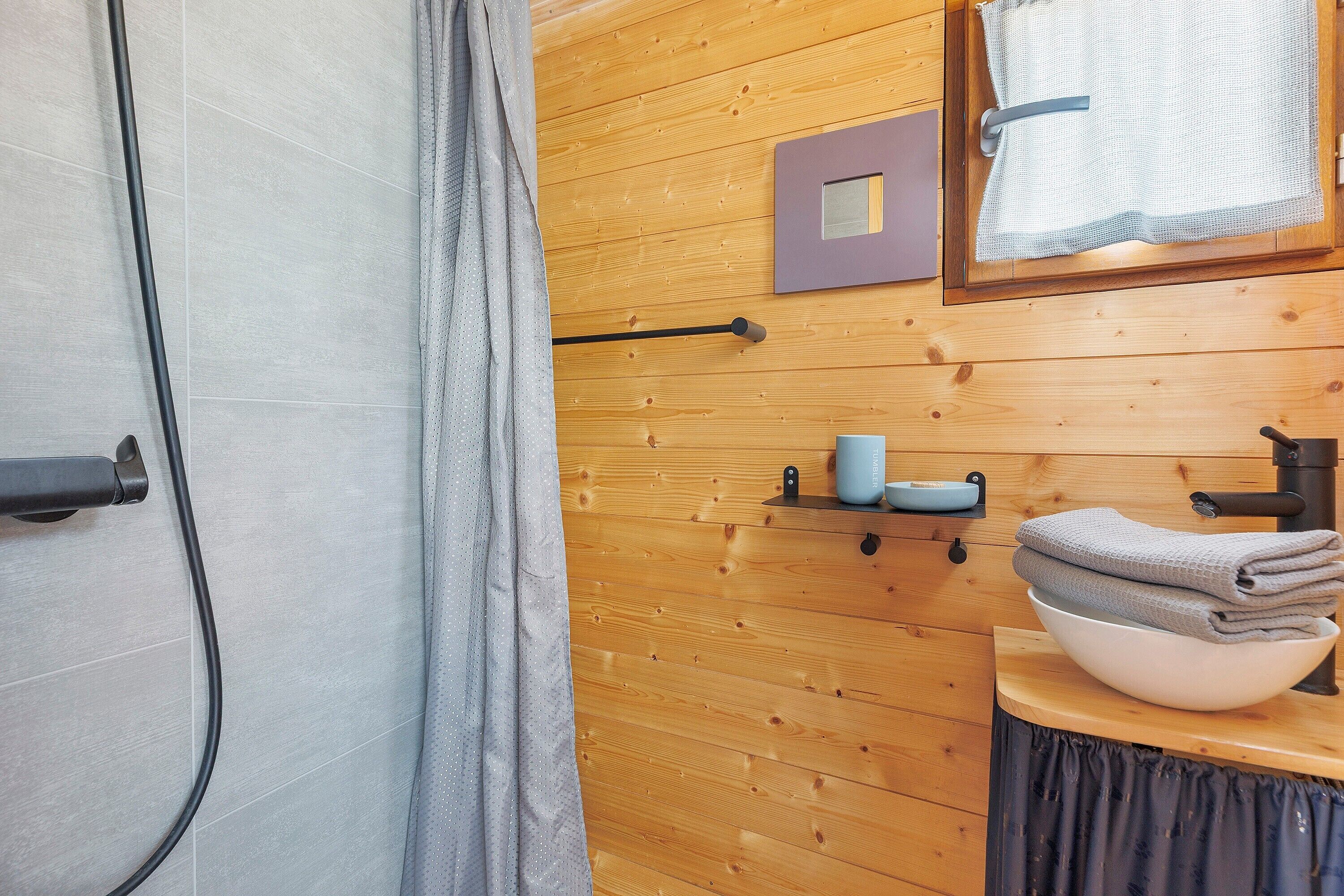 Une salle de bain avec un mur en bois, un porte-serviettes, un lavabo avec un receveur et un rideau de douche.