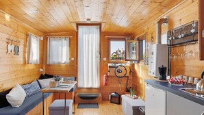 A cozy cabin interior with a wooden interior, a dining area, a kitchen, and a small seating area.