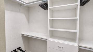 Un vestidor con estantes abiertos, barra para colgar y una silla negra.
