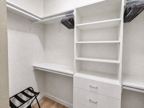Un vestidor con estantes abiertos, barra para colgar y una silla negra.
