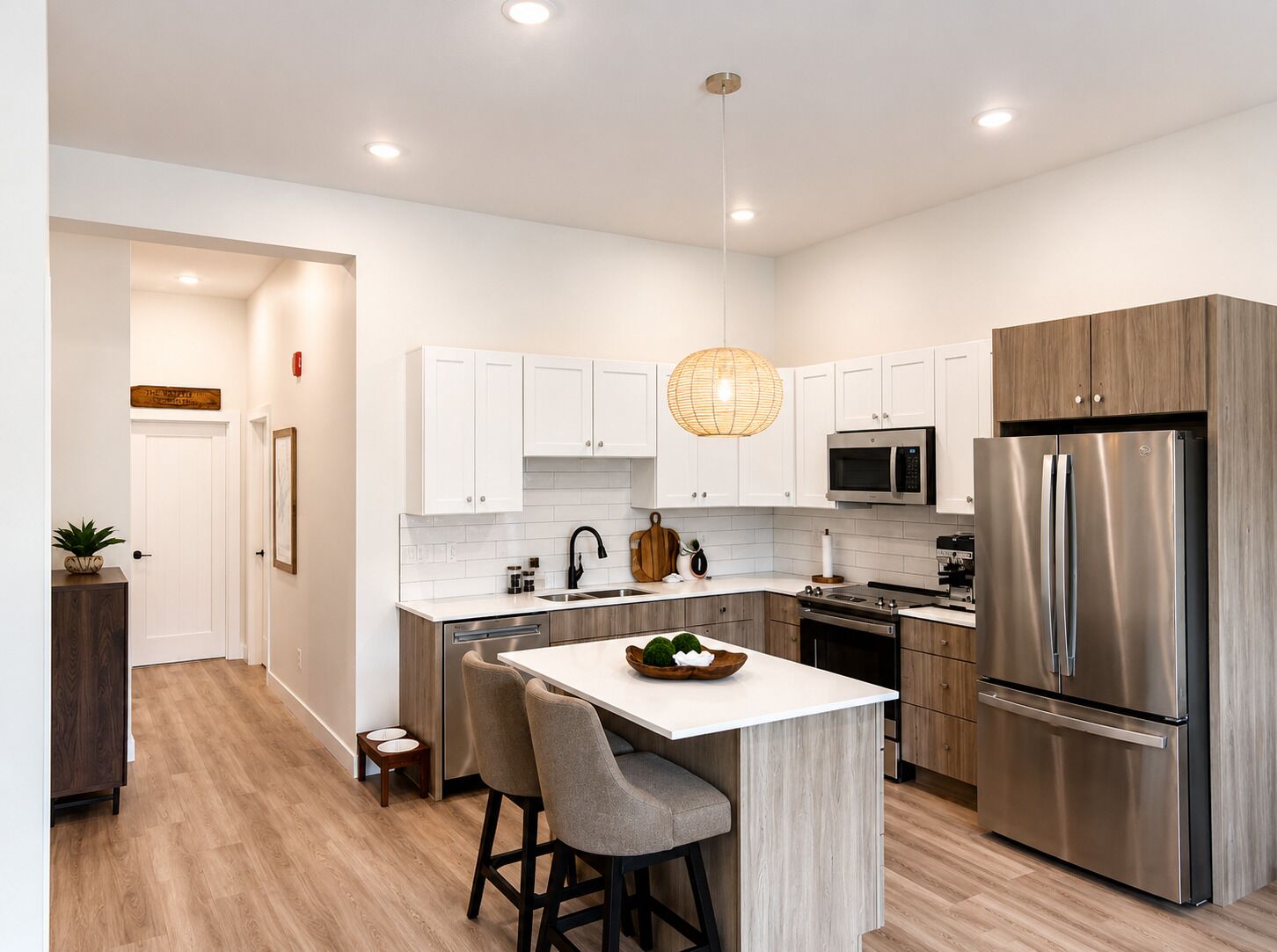 A modern kitchen with white cabinets, stainless steel appliances, and a central island with bar stools.