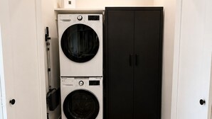 A laundry room with two stacked washing machines and a black cabinet.