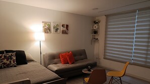 Ein modernes Wohnzimmer mit einer Couch, zwei Sesseln, einem Couchtisch und Wandbildern.